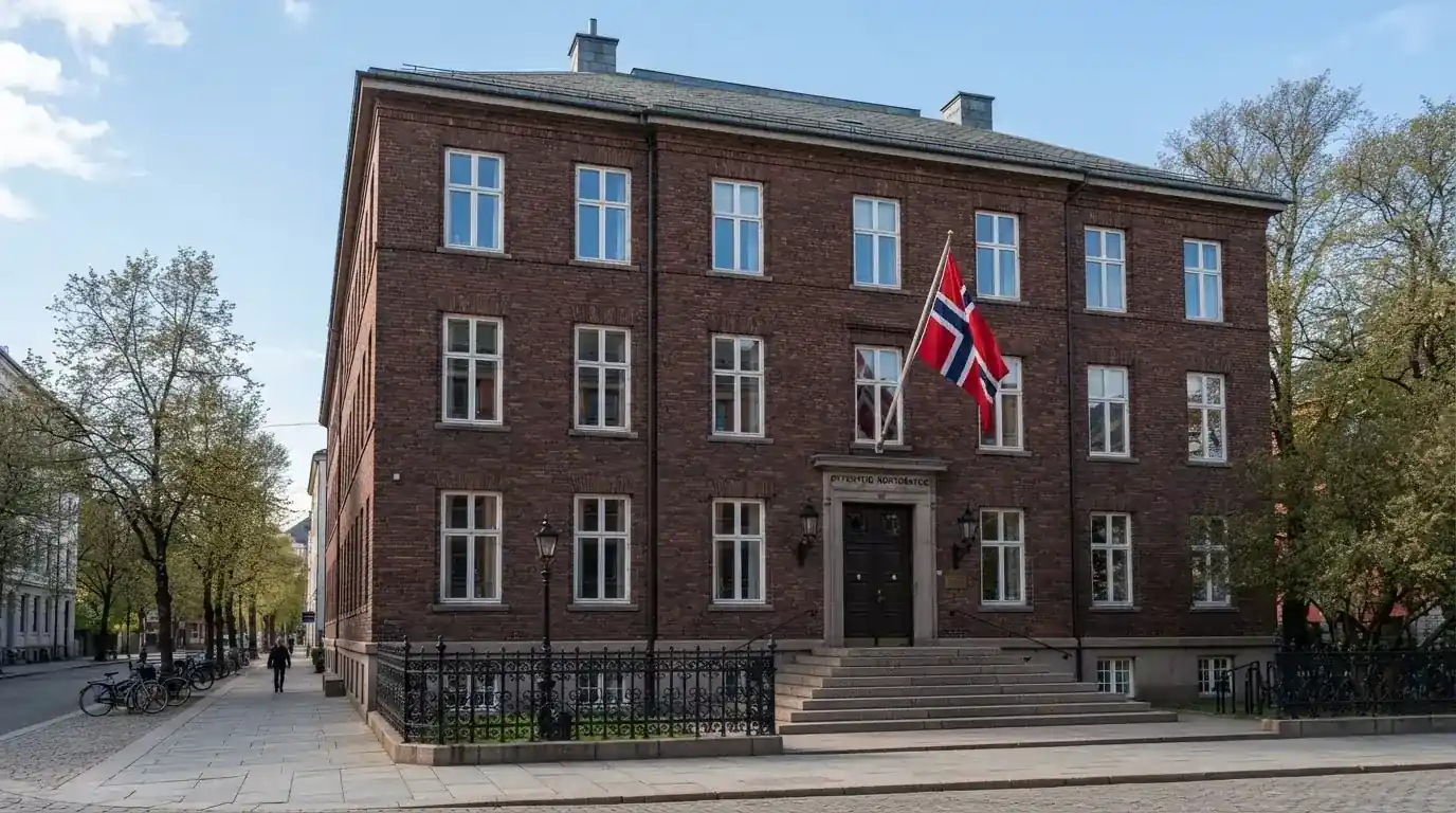 Offentlig kontorbygning i rødt murstein i en norsk by, med et flagg ved inngangen og blå himmel